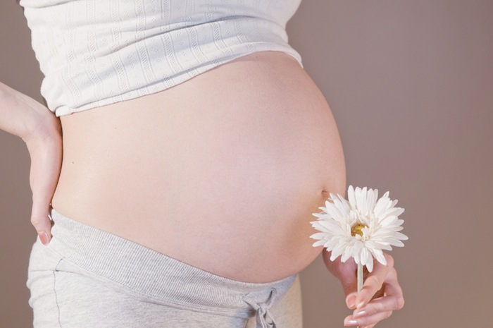 Belly of a pregnant woman with flower.