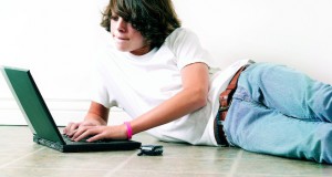 Teenage boy on floor using laptop