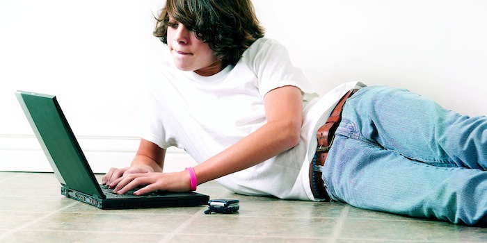 Teenage boy on floor using laptop
