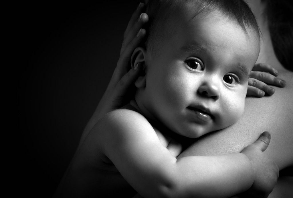 cute baby looking at hands of the mother in an embrace monochrome