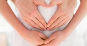 Husband forming heart-shape on pregnant wifes stomach