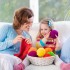 Mother and daughter knitting woolen scarf. Mom teaching child to knit. Crafts and hobby for parents and kids. Toddler girl kid with wool yarn in a basket. Knitted clothing for family with children.
