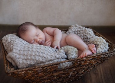 One month old baby boy in the basket on the wooden floor